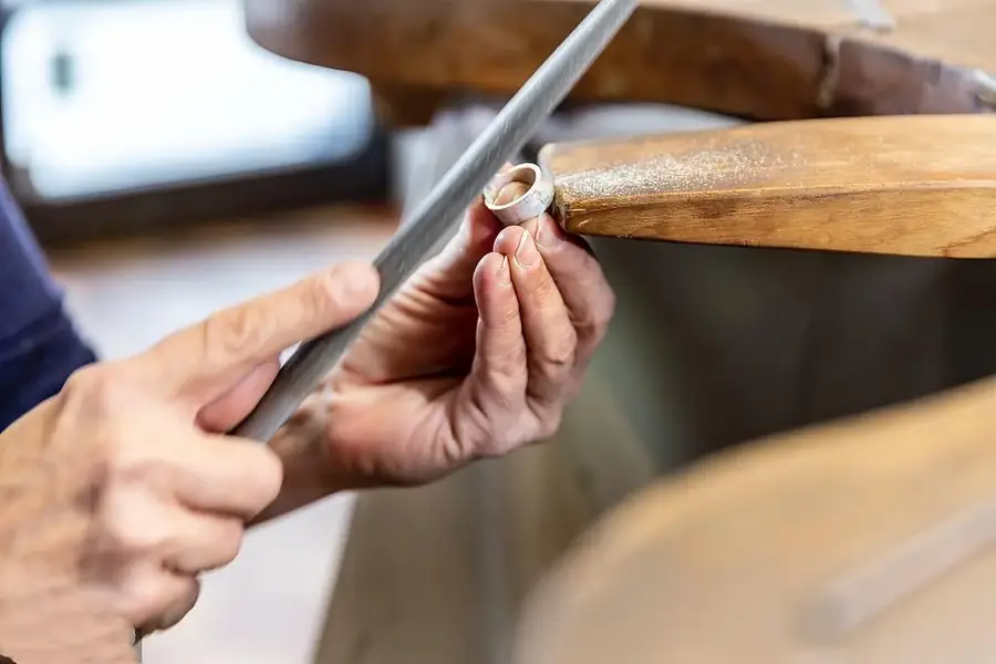 Jewelry artisan filing and shaping a ring by hand